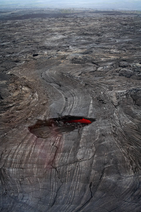 Une crevasse dans le sol volcanique laisse voir de la lave rougissante