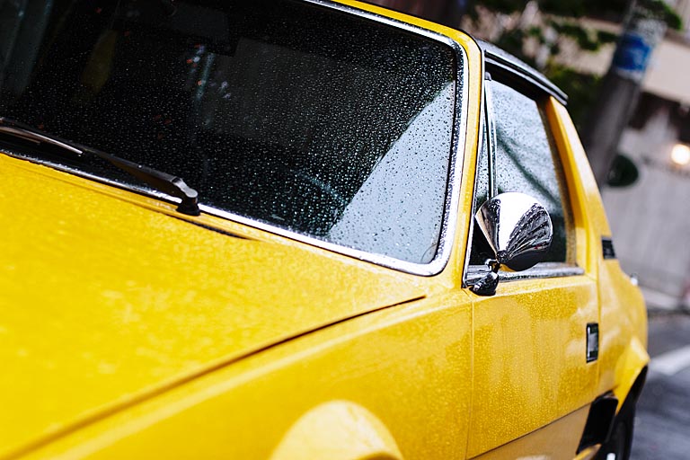 Une vieille voiture jaune dans la pluie